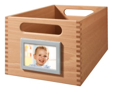 Eine hölzerne Aufbewahrungsbox mit Schwalbenschwanzverbindungen, mit zwei großen Griffausschnitten und einem Schlitz auf der Vorderseite, in den ein Foto eines lächelnden Kindes passt.