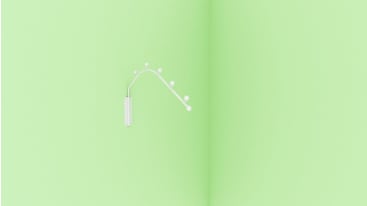 Ein weißes Intrauterinpessar (IUP) mit einem gebogenen Stiel und mehreren kleinen runden Knoten ist vor einem schlichten, hellgrünen Hintergrund abgebildet.