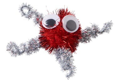 Eine Bastelfigur aus einem roten Lametta-Bommel mit zwei großen Kulleraugen und vier silbernen Lametta-Pfeifenputzern als Gliedmaßen vor einem weißen Hintergrund.
