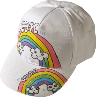 Eine weiße Baseballmütze mit handgezeichneten Regenbögen, Wolken und dem Wort CUTE in bunten Buchstaben auf der Vorderseite und am Rand.