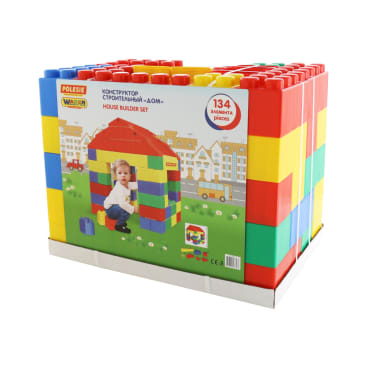 Ausgestellt ist ein verpacktes Hausbauset mit 134 bunten Kunststoffteilen. Die Verpackung zeigt ein Kind, das ein kleines Spielhaus baut, mit illustrierten Häusern und Autos im Hintergrund.