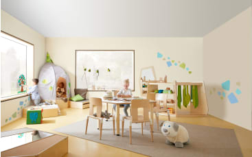 Ein helles, modernes Spielzimmer mit drei spielenden Kindern. Das Zimmer hat Holzmöbel, große Fenster, ein Spielzelt, Regale, einen Teppich und Spielzeug, darunter ein Plüschtier und Bauklötze. Von draußen fällt Licht ins Zimmer.