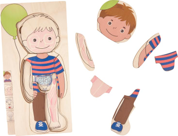 Ein Holzpuzzle, das einen Jungen zeigt, der einen grünen Luftballon hält. Einige Teile, darunter der Kopf, der Arm und das Bein, werden entfernt und zur Seite gelegt, so dass die inneren Organe des darunter liegenden Rumpfes sichtbar werden.