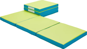 Ein Stapel von drei gefalteten Turnmatten in Blau und Hellgrün neben einer ungefalteten Matte derselben Farbe und desselben Designs, die flach auf einem weißen Hintergrund liegt.