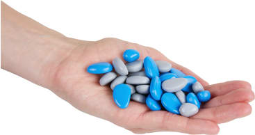 Eine Hand hält einen Stapel glatter, ovaler Bonbons oder Steine in blauen und grauen Farben vor einem weißen Hintergrund.