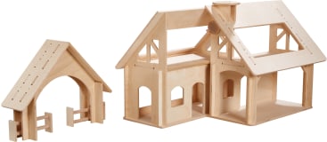 Ein hölzernes Puppenhaus mit einem bogenförmigen Eingangstor und einem Zaun auf der linken Seite und ein größeres zweistöckiges Haus mit offenen Fenstern und Dachteilen auf der rechten Seite, beide aus unbearbeitetem Holz.