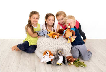 Vier kleine Kinder sitzen auf dem Boden um einen gestrickten Hocker herum und halten verschiedene Tierhandpuppen, darunter ein Löwe, ein Hund, eine Eule, ein Nashorn und ein Truthahn, vor einem schlichten weißen Hintergrund.