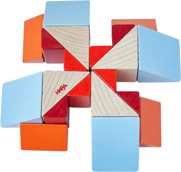 Eine geometrische Anordnung von Holzspielzeugblöcken in Rot, Orange, Blau und natürlichen Holzfarben, die ein symmetrisches, pinradähnliches Muster bilden. Die Blöcke bestehen aus Würfeln und Dreiecken. Auf einem Block ist das Wort HABA aufgedruckt.