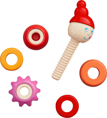 Ein Holzspielzeug mit lächelndem Gesicht und roter Kappe in Form einer Schraube ist von fünf bunten kreisförmigen und zahnradförmigen Ringen in Rot, Orange, Gelb und Rosa auf weißem Hintergrund umgeben.