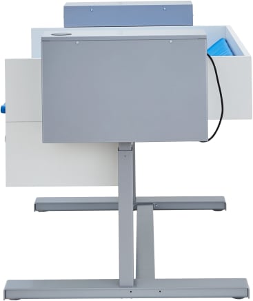 Ein grauer und weißer verstellbarer Stehschreibtisch mit einem blauen Gegenstand in einer offenen Schublade, von der Rückseite aus gesehen. Der Schreibtisch hat einen Metallrahmen und ein Kabel, das von der rechten Seite herabhängt.