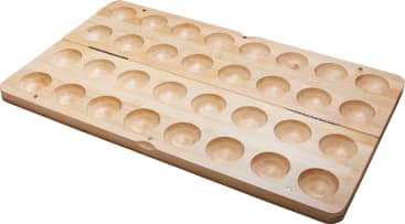 Ein hölzernes Mancala-Brett mit zwei Reihen von sechs kleinen runden Vertiefungen auf jeder Seite und zwei größeren Vertiefungen an jedem Ende, das zum Spielen des traditionellen Mancala-Spiels verwendet wird.
