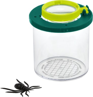 Ein durchsichtiges Plastikbeobachtungsglas mit einem grünen und gelben Vergrößerungsdeckel steht neben einem schwarzen Plastikmodell einer Spinne auf weißem Hintergrund. Das Glas hat ein Gittermuster auf seinem Boden.