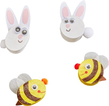 Vier kleine Basteleien aus ovalen Formen: zwei weiße Kaninchen mit rosa Ohren, Kulleraugen und Bommelschwänzen und zwei gelbe Bienen mit braunen Streifen, Flügeln, Kulleraugen und orangefarbenen Bommelnasen.