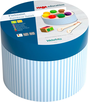 Eine runde, blau-weiß gestreifte Schachtel mit der Aufschrift HABA Education Farbsalat Rainbow Salad. Der Deckel zeigt bunte Holzspielzeug und Utensilien, mit Produktinformationen in mehreren Sprachen.