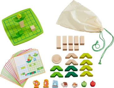 Ein Tischspielset mit einem grünen Spielbrett, einer Stofftasche mit Kordelzug, Holzklötzen, runden und eckigen Holzteilen, illustrierten Karten sowie Tier- und Apfelplättchen auf weißem Hintergrund.