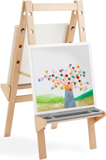Eine hölzerne Staffelei hält eine Leinwand, die einen bunten Baum aus gerolltem Papier zeigt. Die Staffelei hat ein Tablett am Boden und ein weiteres leeres Brett hinter der Leinwand.