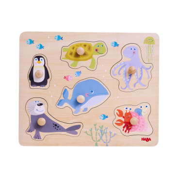 Ein hölzernes Puzzlebrett mit fünf Tierteilen: Pinguin, Schildkröte, Krake, Wal und Robbe. Jedes Teil hat einen Knauf für eine einfache Handhabung. Auf dem Brett sind außerdem kleine Fische, Seetang und eine Krabbe abgebildet.