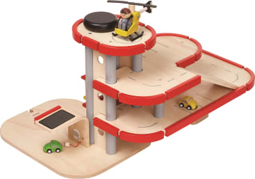 Ein hölzernes Spielzeugparkhaus mit drei Etagen, roten Geländern, Rampen, kleinen Spielzeugautos, einer Zapfsäule und einem Hubschrauber mit einer Figur auf dem Hubschrauberlandeplatz auf dem Dach.