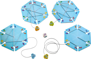 Vier sechseckige blaue Spielbretter mit Spinnennetzmustern liegen auf einer weißen Fläche, jedes mit farbigen Spielsteinen und einer Schnur, an der eine Spinnenfigur befestigt ist. In der Mitte befindet sich ein sechsseitiger Würfel mit Symbolen.