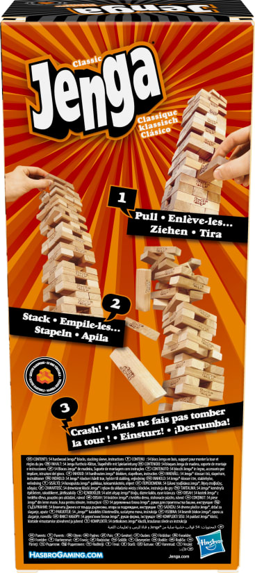 Eine Schachtel für das klassische Jenga-Spiel zeigt Hände, die Holzblöcke ziehen und stapeln. Der Hintergrund ist orange mit Strahlen, und die Anweisungen erscheinen in mehreren Sprachen. Das Hasbro Gaming Logo befindet sich unten rechts.