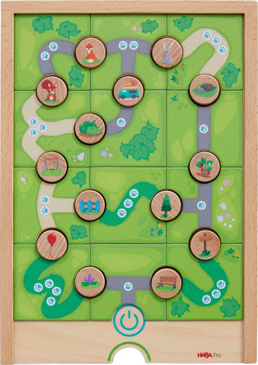 Ein hölzernes Puzzlespielbrett mit grünen Pfaden und zwölf runden Holzplättchen, die Bilder wie Tiere, ein Auto, einen Ballon, Bäume und eine Blume zeigen. Das Spielbrett hat ein blaues Machtsymbol in der unteren Mitte.