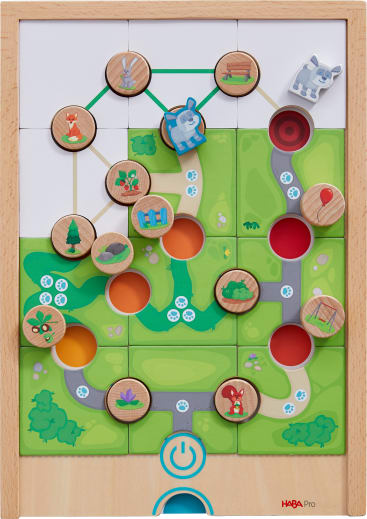 Ein Brettspiel aus Holz mit kreisförmigen Spielsteinen, die Tiere, Bäume und Häuser zeigen, die durch Linien verbunden sind. Der Hintergrund besteht aus grünen Feldern, Wegen und farbigen Kreisen. Ein blaues Machtsymbol befindet sich in der unteren Mitte.