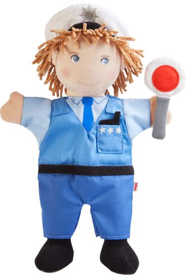Eine weiche Stoffpuppe in einer blauen Polizeiuniform mit schwarzen Schuhen, einer weißen Polizeimütze und drei Sternen auf der Hemdtasche, die einen grauen Stock mit einem rot-weißen Kreis am Ende hält.