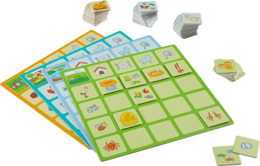 Vier farbenfrohe Spielbretter mit Tier- und Objektillustrationen sind abgebildet, jeweils mit passenden quadratischen Spielsteinen. Zusätzliche Stapel von Plättchen mit ähnlichen Abbildungen liegen über und neben den Brettern.