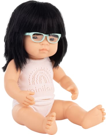 Eine Babypuppe mit glattem schwarzem Haar, heller Haut und einer mintgrünen Brille sitzt aufrecht und trägt ein weißes, ärmelloses Outfit mit einem gepunkteten Bogenmuster.