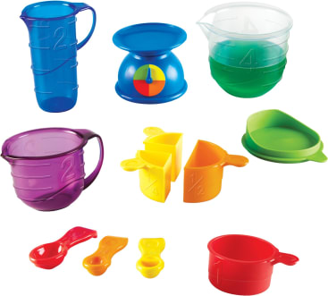 Ein Satz bunter Plastikmessbecher, Löffel, Krüge, eine Waage und eine grüne Pfanne sind auf einem weißen Hintergrund angeordnet. Die Gegenstände sind in verschiedenen Größen und Farben gehalten, darunter blau, lila, grün, gelb, rot und orange.