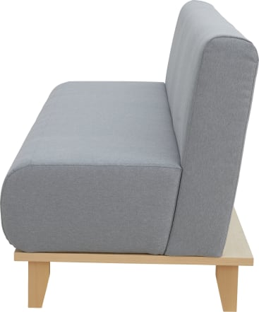 Seitenansicht eines modernen Sofas mit hellgrauen Kissen und einem hellen Holzrahmen, das sich durch einfache, klare Linien und keine sichtbaren Armlehnen auszeichnet.